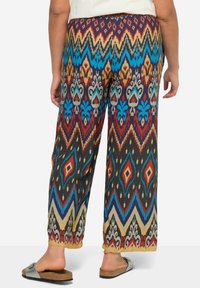 Wielokolorowe spodnie o szerokich nogawkach z zygzakowym wzorem, w tym diamenty i motywy kwiatowe. Wykonane z lekkiego, gładkiego materiału.