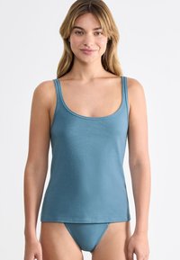 Top in tessuto azzurro chiaro con spalline sottili, realizzato in materiale morbido, con scollatura rotonda e design aderente. Parte inferiore del bikini abbinata visibile.