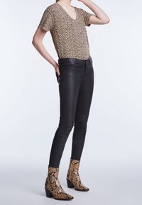 Halenka s krátkým rukávem a výstřihem do V v leopardím vzoru, černé skinny džíny a kotníkové boty se vzorem hada na blokovém podpatku.