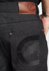 Zwarte denimshorts met een leren patch op de taille die de merknaam benadrukt. Heeft een getextureerde zak met een gewatteerd ontwerp.