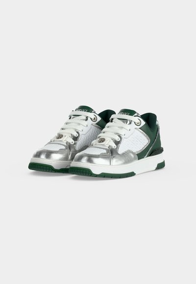 Paire de baskets basses avec des panneaux argentés, blancs et vert foncé, lacets blancs et semelles épaisses blanches avec des crampons vert foncé.