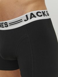 Schwarze Baumwollboxershorts mit einem weißen elastischen Bund, auf dem "JACK & JONES" in Schwarz gedruckt ist. Glatte Textur und körperbetontes Design.