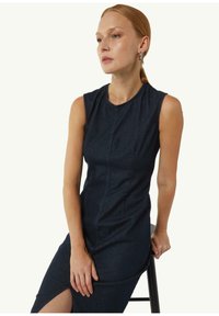 Ciemnoniebieska, bez rękawów sukienka z okrągłym dekoltem, przednim szwem i wycięciem do uda. Gładka tekstura i dopasowany krój.