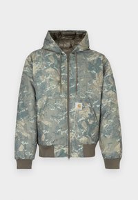 Prešívaná bunda s kapucňou v zelenej a béžovej kamuflážnej vzore. Má zapínanie na zips, šnúrky a rebrované manžety a lem. Obsahuje nášivku s logom.