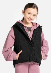 Czarna kamizelka puchowa z kapturem, z przodem zapinanym na guziki i bocznymi kieszeniami, noszona na jasnoróżowej bluzie.