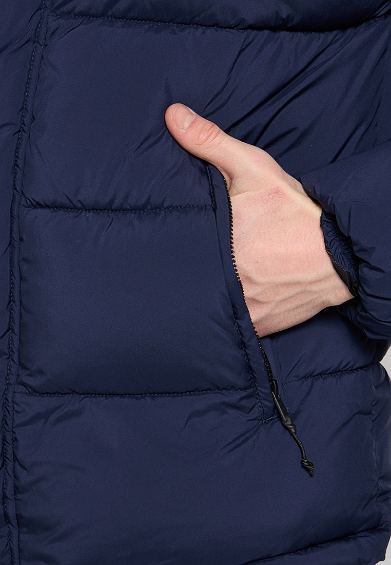 Granatowa kurtka puchowa z pikowanym wzorem, boczną kieszenią na zamek oraz regulowanym ściągaczem dla lepszego dopasowania.