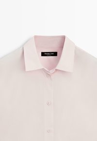 Světle růžová košile na knoflíky s špičatým límečkem a třemi viditelnými knoflíky, uvnitř límce je černá etiketa Massimo Dutti.