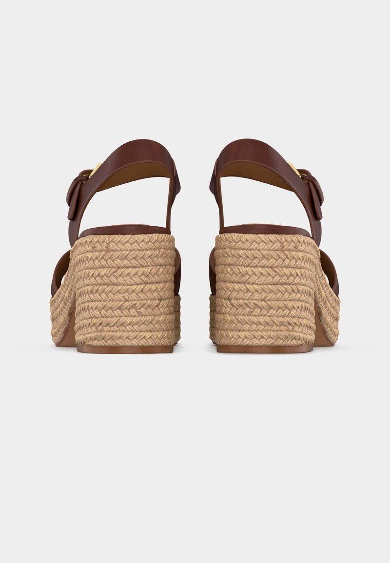 Paire de sandales en cuir marron avec talons carrés tressés à texture de corde, vues de dos sur un fond clair uni.