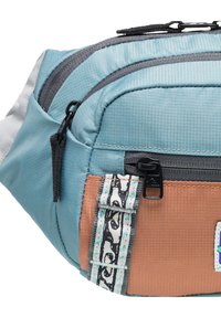 Fanny packki sininen ja oranssi materiaali, jossa on teksturoitu pinta. Sisältää useita vetoketjullisia osastoja ja kuviollisen säädettävän hihnan.