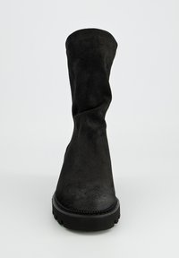 Botte haute en suède noir, au design décontracté, finition texturée et semelle en caoutchouc épais et durable. Aucun matériel ou accent visible.