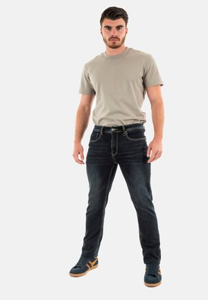 Jeans de color azul oscuro con un corte slim, combinados con una camiseta de manga corta gris claro. Zapatillas con tela azul oscuro y acentos naranjas.