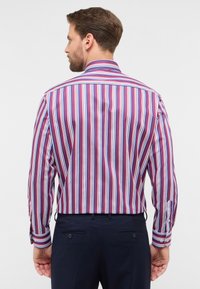 Camicia da uomo a maniche lunghe con strisce verticali rosse, blu e bianche. Presenta un colletto classico e polsini con bottoni, realizzata in tessuto liscio.