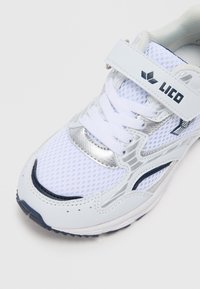 Λευκό και ασημί αθλητικό παπούτσι με πλέγμα στο πάνω μέρος, διαθέτει κορδόνια και λευκή ρυθμιζόμενη φάσα με μαύρο λογότυπο "LICO".