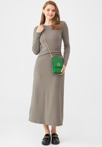 Abito grigio a maniche lunghe con vita aderente e gonna fluente. Abbinato a una borsa a tracolla verde brillante e mocassini neri con dettagli dorati.