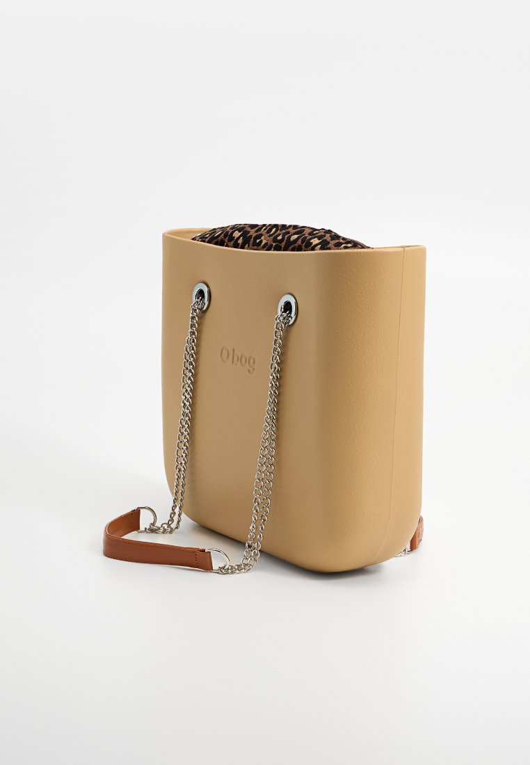 Beżowa torba tote z faux skórki, z srebrnym łańcuchem i brązowym paskiem, z wyściółką w leopardzi wzór widoczną na górze oraz gładkimi, zaokrąglonymi krawędziami.