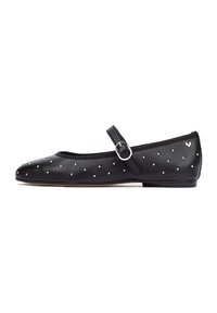 Bailarinas de cuero negro con punta afilada, adornadas con tachuelas plateadas y presentan una correa al estilo Mary Jane con una hebilla redonda.