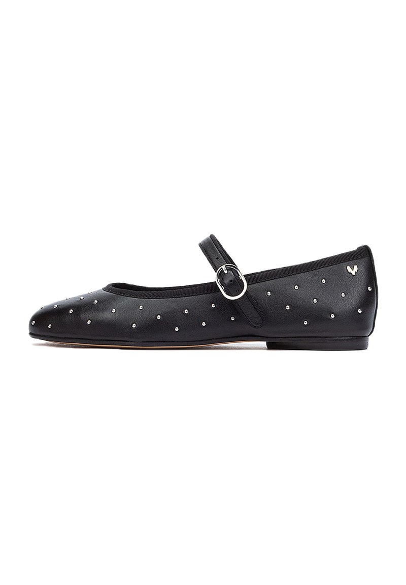 Bailarinas de cuero negro con punta afilada, adornadas con tachuelas plateadas y presentan una correa al estilo Mary Jane con una hebilla redonda.