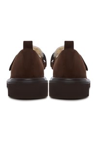 Et par brune ruskinds slip-on sko med tykke såler og synlig cremefarvet pelsforing, set fra bagsiden.