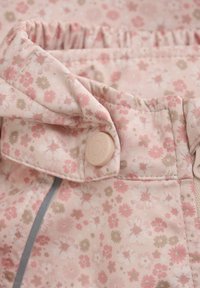 Květinový vzorovaný textil v jemné růžové a béžové barvě, s nařaseným pasem a krémovým knoflíkovým zapínáním s šedým akcentem.