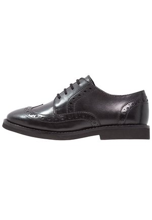 Czarne skórzane eleganckie buty brogue z wzorem wingtip, perforowanymi detalami i czarnymi sznurowadłami, pokazane z boku na białym tle.