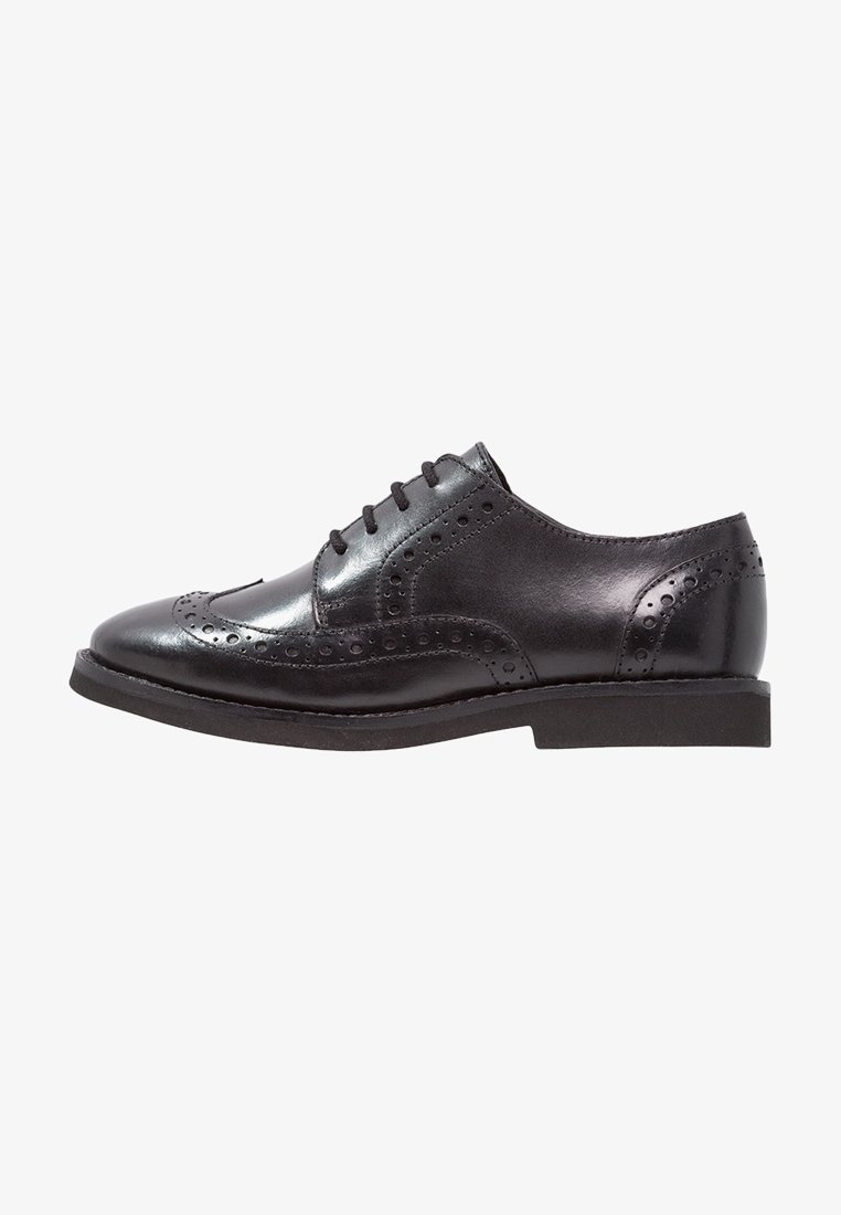 Chaussure habillée brogue en cuir noir avec design à bout ailé, détails perforés et lacets noirs, vue de profil sur fond blanc.