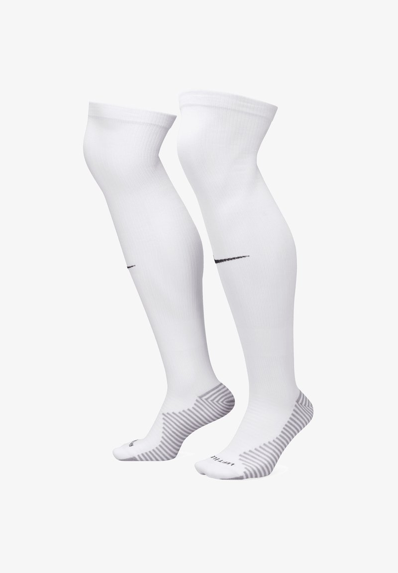 Witte kniekousen van glad materiaal, met een zwart Nike-logo en een gestreept patroon op de zool.