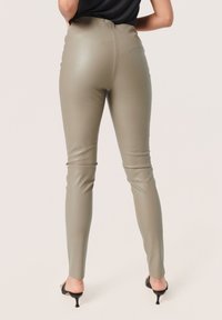 High-waisted, form-fitting pants in olive green faux leather with a smooth texture; features a seamless back and tapered legs.