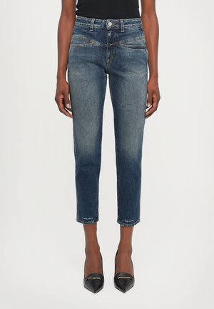 Dark blue denim jeans with a slim fit, mid-rise waist, and cropped length. Features subtle whiskering and a clean hem.
