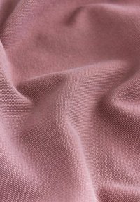 Textilgewebe in einem hellrosa Farbton, mit einer gewebten Textur und kleinen, einheitlichen Mustern. Weich und flexibel mit einer glatten Oberfläche.