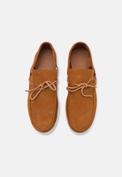 Brown suede shoes with a rounded toe, lace-up design, and a soft texture. Features a white outsole and a simple trim.