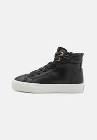 Baskets montantes noires en cuir avec surface texturée, dotées d'œillets dorés, de lacets noirs à pois et d'une semelle en caoutchouc blanche.