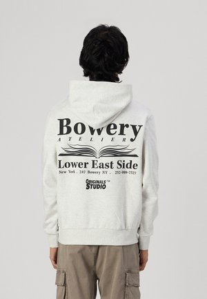 Hellgrauer Kapuzenpullover mit schwarzem Text und Grafikdesign auf der Rückseite. Gerippte Bündchen und Saum sowie eine geräumige Kapuze.