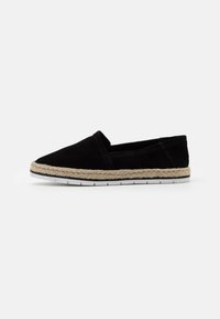 Scarpa slip-on in suede nero con rifinitura in juta intrecciata e suola in gomma bianca, caratterizzata da un design a punta e dettagli di cucitura minimali.