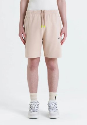 Pantalones cortos beige hechos de una tela suave, con una cinturilla elástica y cordones de neón, bolsillos laterales y un pequeño logo en la parte frontal.
