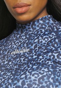 Blue leopard print long-sleeve top with a high collar. Soft fabric with a smooth texture. Featured logo in white on the chest area.