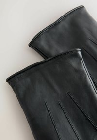 Black leather gloves with a smooth texture, featuring vertical stitching lines and a fitted design. Bottom edges are rounded.