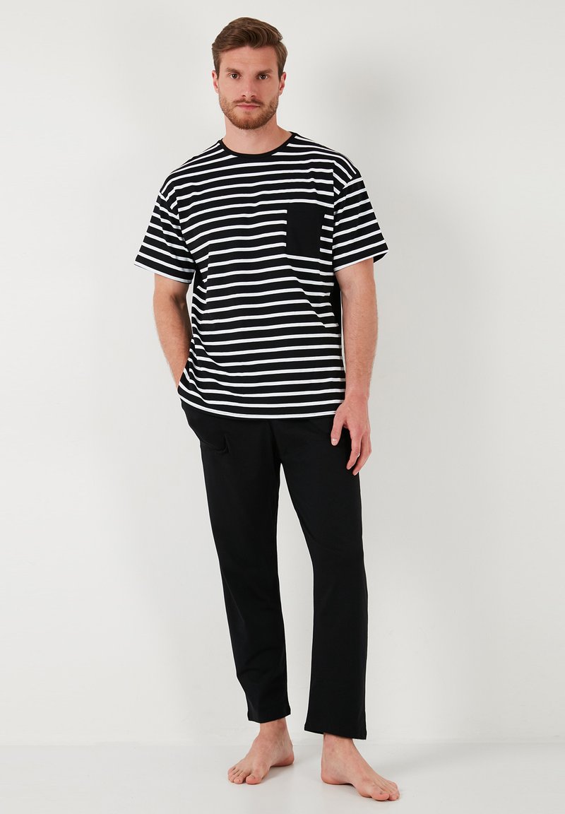 Tricou cu mânecă scurtă, cu dungi alb-negru și buzunar pe piept, asortat cu pantaloni negri, cu croială dreaptă. Material neted, tăietură lejeră, design minimalist.