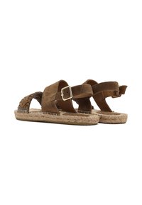 Sandali in suede marrone con cinturino intrecciato, fibbia alla caviglia e suola in corda intrecciata. Texture liscia con silhouette piatta.