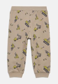 Μπεζ βαμβακερό παντελόνι με ελαστική μέση, διακοσμημένο με επαναλαμβανόμενο σχέδιο κίτρινων κατασκευαστικών οχημάτων και εργαλείων με μαύρη περίγραμμα.