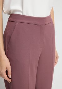 Mauve op maat gemaakte broeken met een gladde textuur, voorzien van zijzakken en een platte tailleband. De pasvorm is slank en modern.