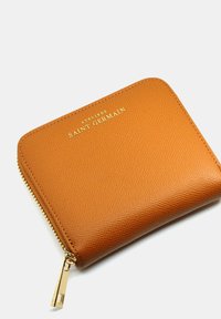 Portefeuille en cuir marron avec une finition texturée, logo doré "ATELIERS SAINT GERMAIN" et fermeture éclair dorée. Forme compacte et rectangulaire.