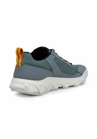 Scarpa sportiva grigia con tomaia in rete testurizzata, suola bianca spessa e un vivido laccio arancione sul tallone. I lacci presentano più colori.