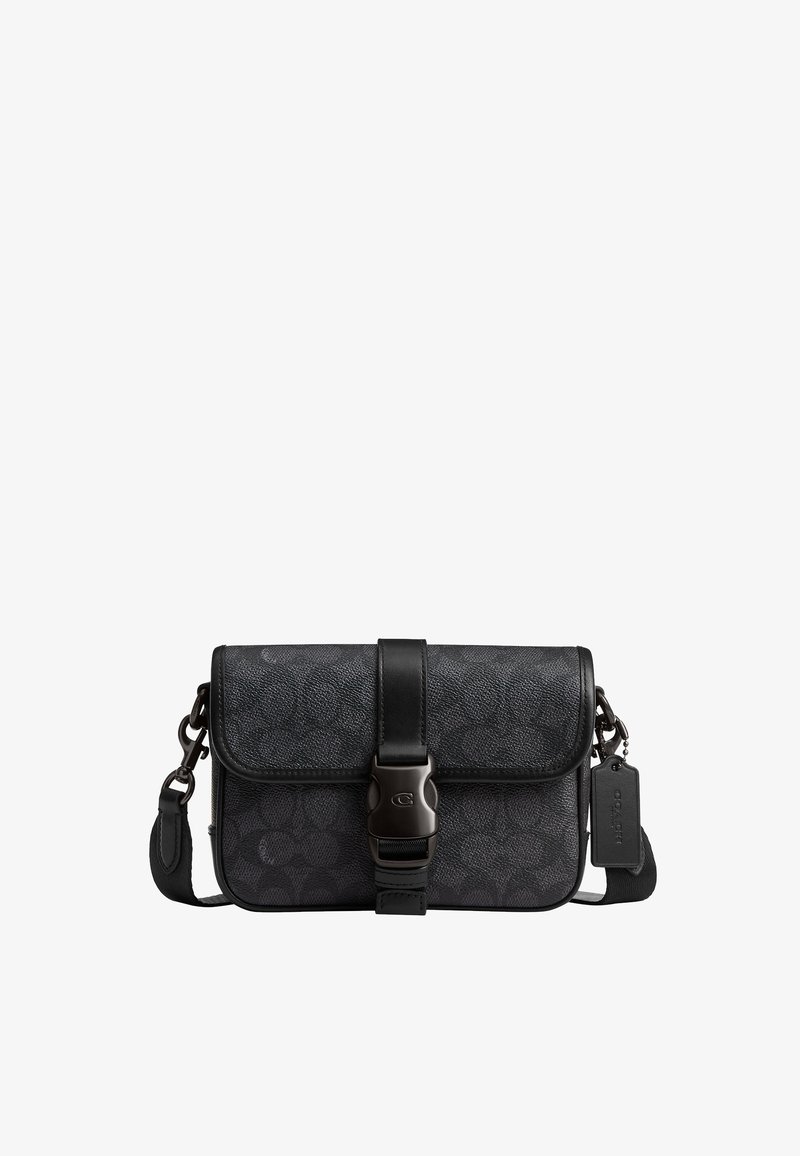 Bolso bandolera negro con textura, con correa ajustable, cierre frontal con hebilla y una pequeña etiqueta en un lateral.