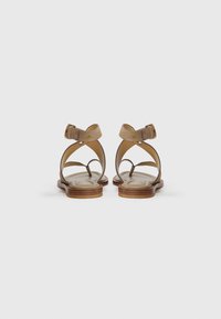 Beige leather sandals with crisscross straps, back ankle buckle, padded insole, and wooden sole, featuring a smooth finish and minimal design.