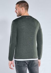 Dunkelgrüner Pullover mit langen Ärmeln und rundem Ausschnitt, hergestellt aus einem glatten Strickstoff. Verfügt über ein kleines Logoetikett auf der Rückseite.