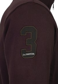 Maroon sweatshirt with a high collar and zip, featuring a large black embroidered number 3 and "la martina" logo on the sleeve.