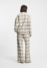 Plaid loungewear set in soft, brushed fabric. Long-sleeve top with lapel collar, matching wide-leg pants. Colors include beige, light blue, and cream.