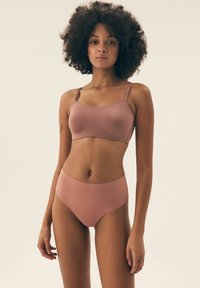Soft pink bra and high-waisted brief set, made from smooth fabric, featuring adjustable straps and seamless edges for comfort.
