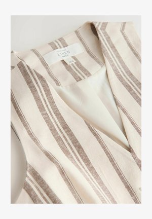 Bēša un brūna svītrota lina veste ar V veida kakla izgriezumu un baltu iekšējo oderējumu, salocīta plakani, redzama kakla etiķete.