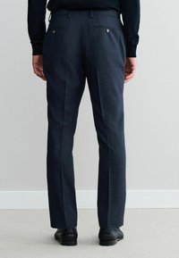 Dunkelgraue maßgeschneiderte Hose mit einem dezenten Karomuster, ausgestattet mit zwei Gesäßtaschen mit Knopfverschluss und einem geraden Schnitt.